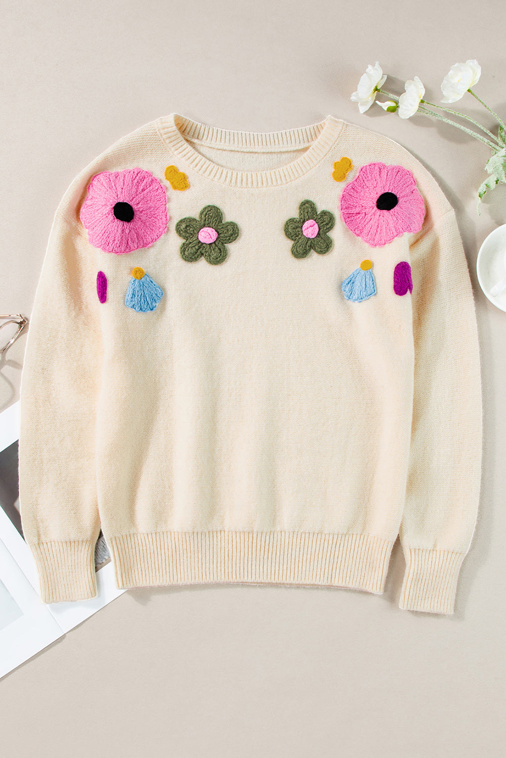 Beige gestrickter pullover mit blumenmuster und geripptem rand