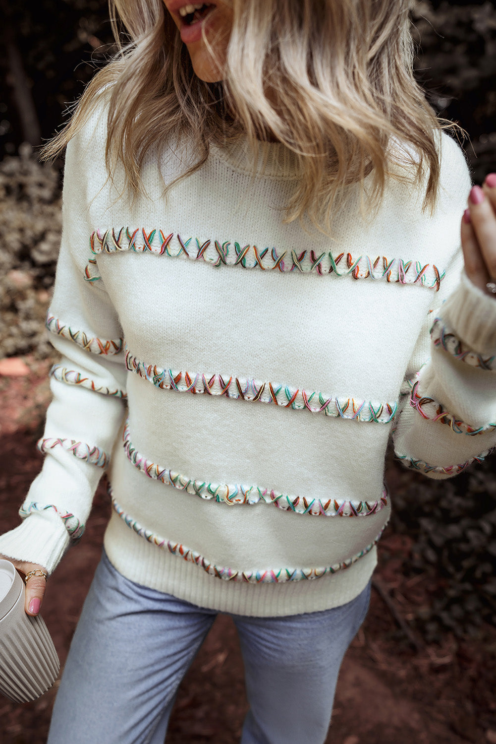 Weißer pullover mit gekreuzten schultern und bunten maschen
