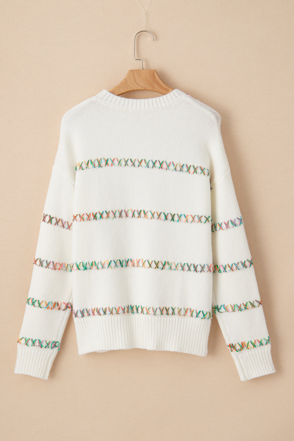 Weißer pullover mit gekreuzten schultern und bunten maschen