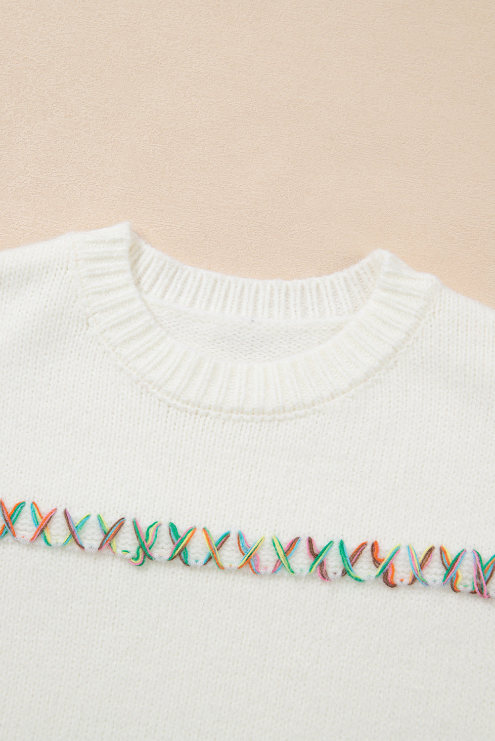 Weißer pullover mit gekreuzten schultern und bunten maschen