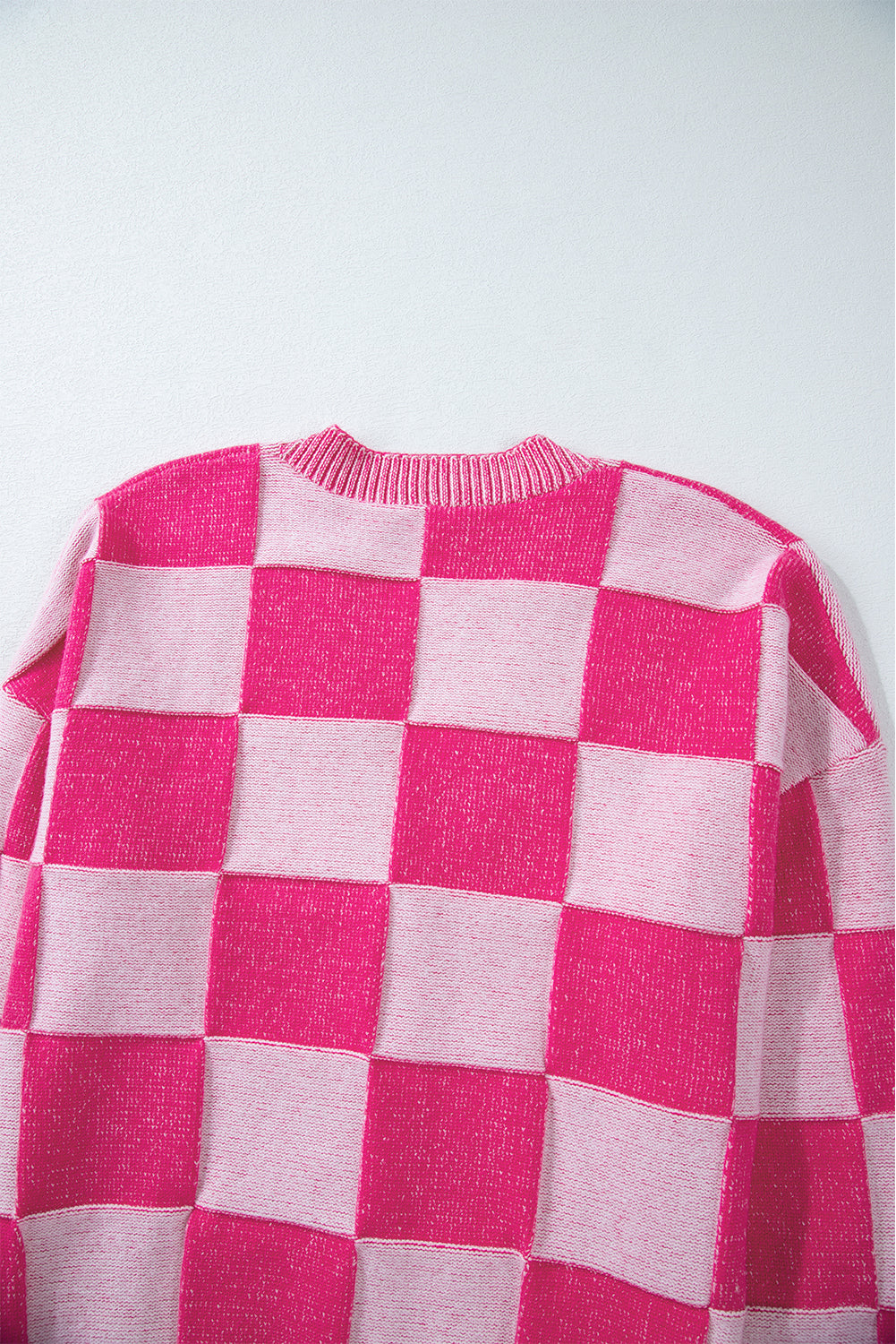 Rosa karierte strickjacke mit v-ausschnitt und geknöpften schultern
