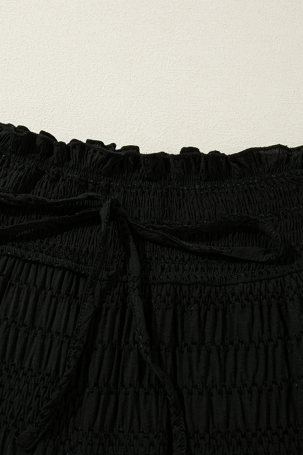 Schwarze strukturierte hose mit breiter gesmokter taille und loser hose