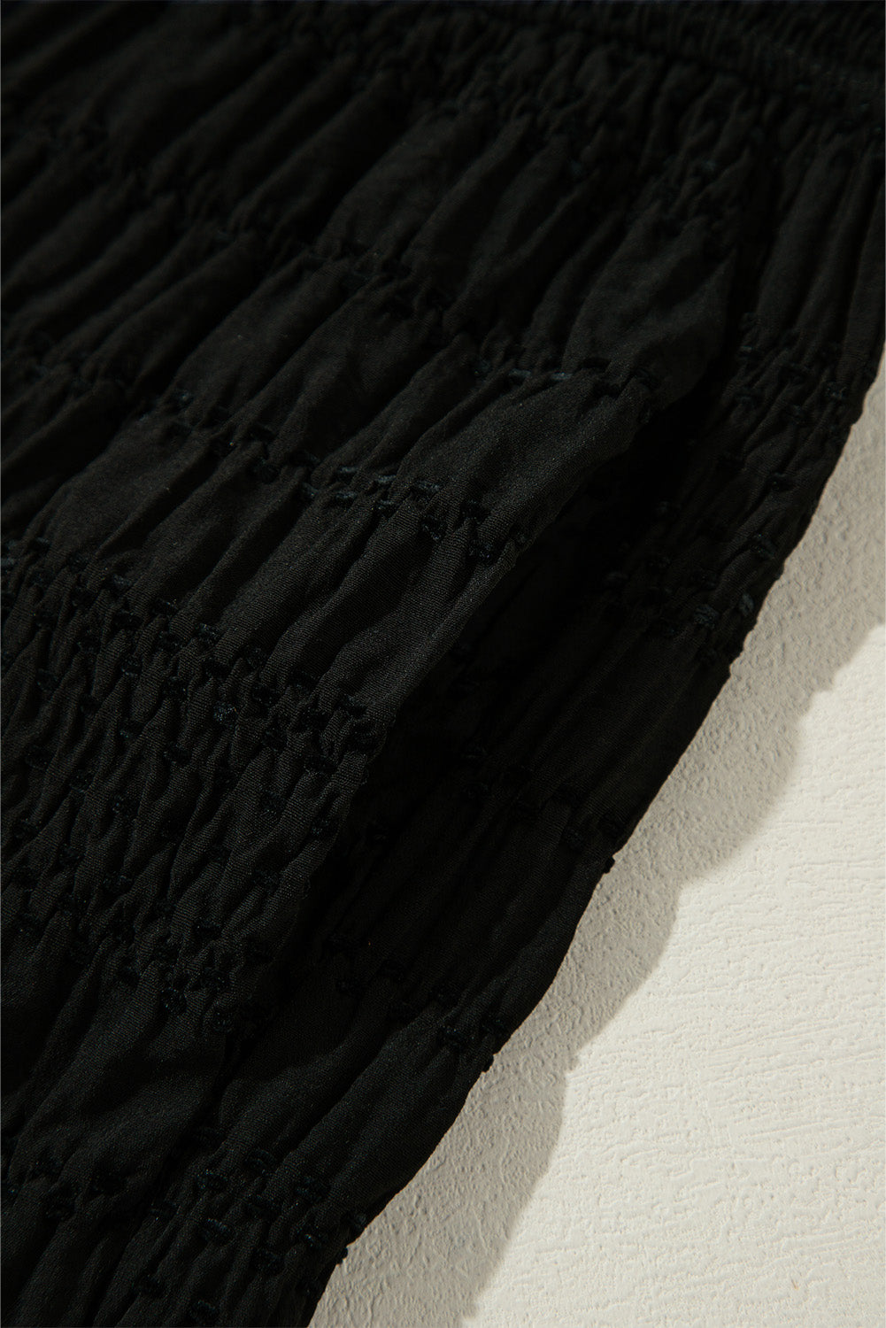 Schwarze strukturierte hose mit breiter gesmokter taille und loser hose