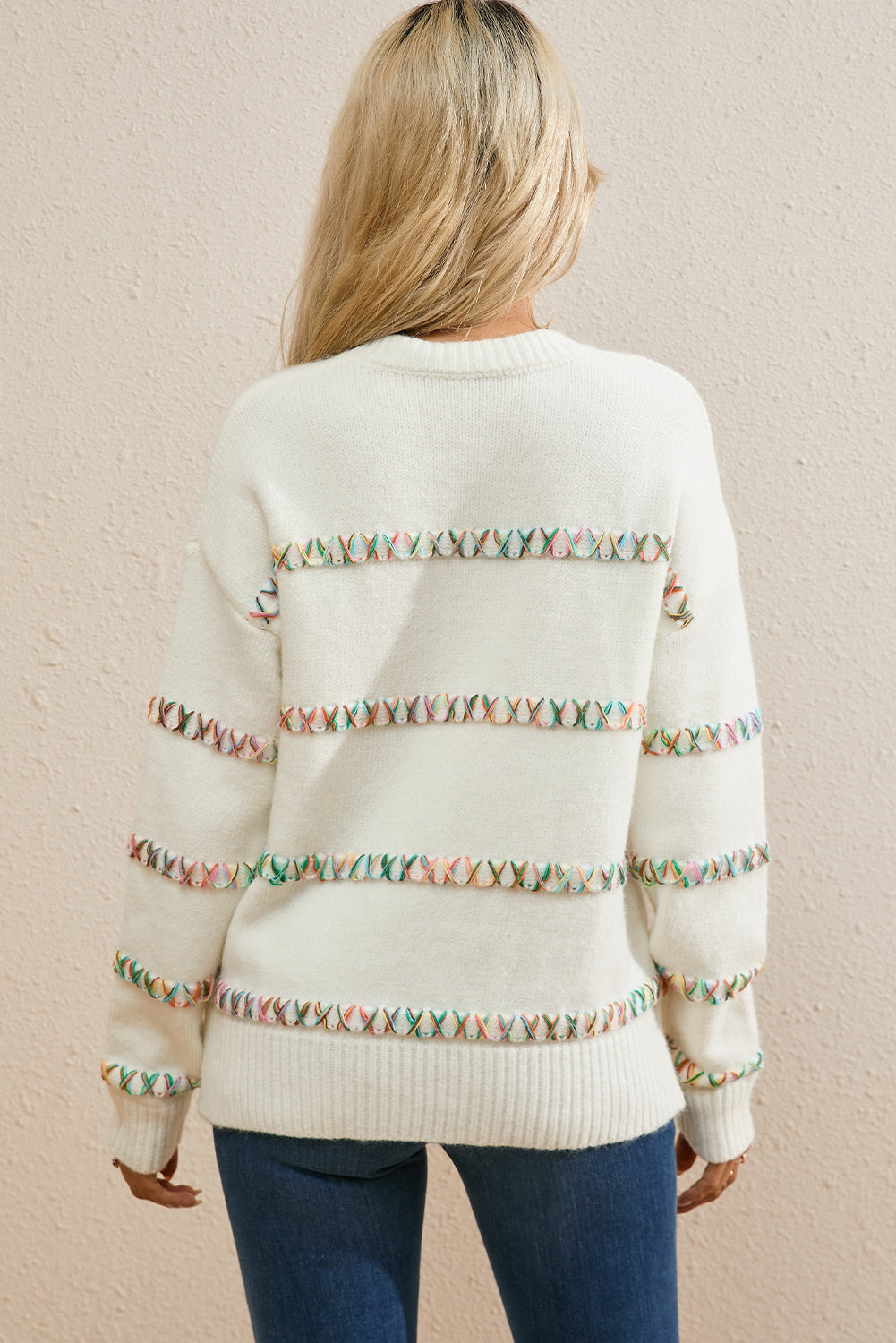 Weißer pullover mit gekreuzten schultern und bunten maschen