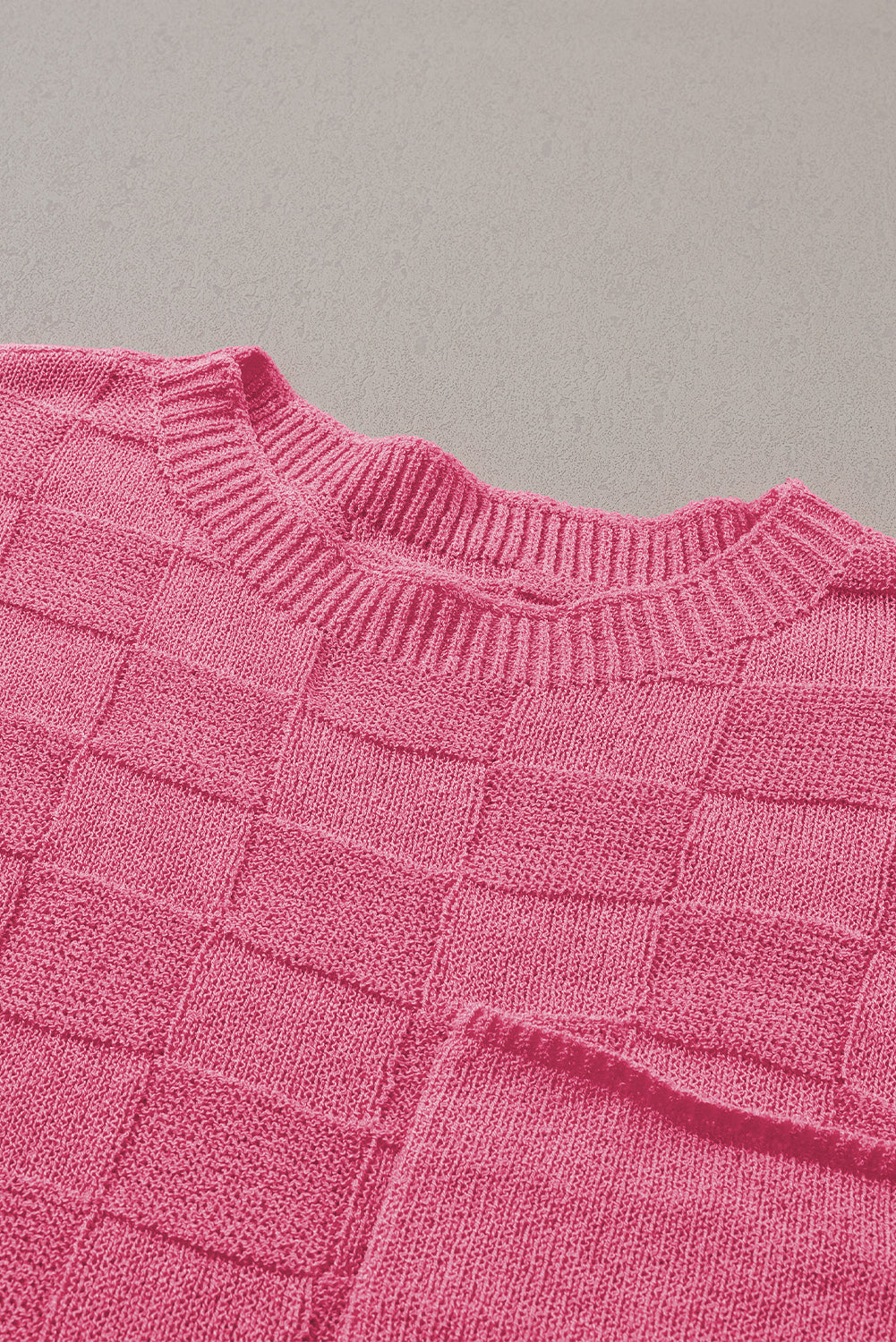 Leuchtend rosafarbener strickpullover mit kurzen ärmeln und gitterstruktur