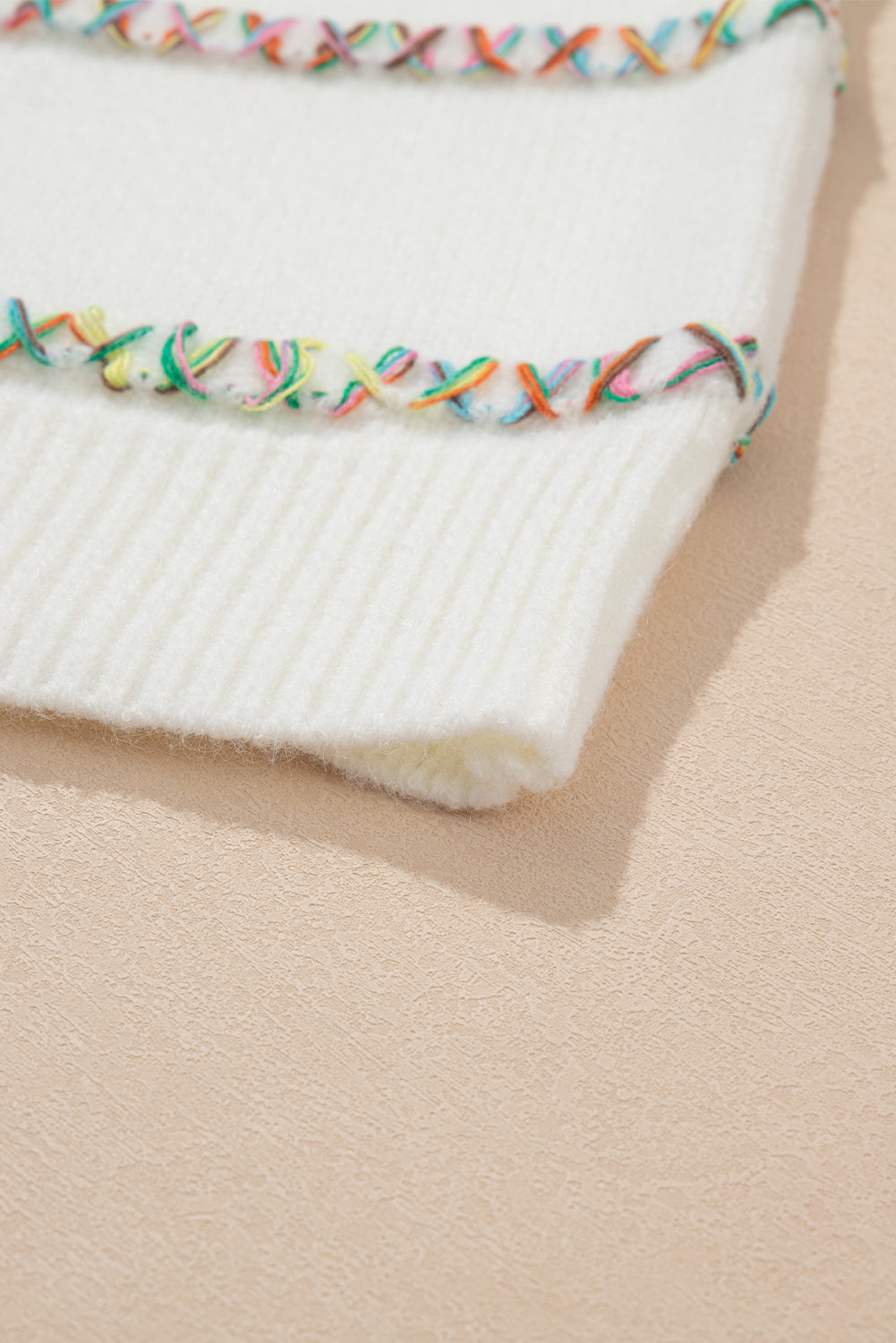 Weißer pullover mit gekreuzten schultern und bunten maschen