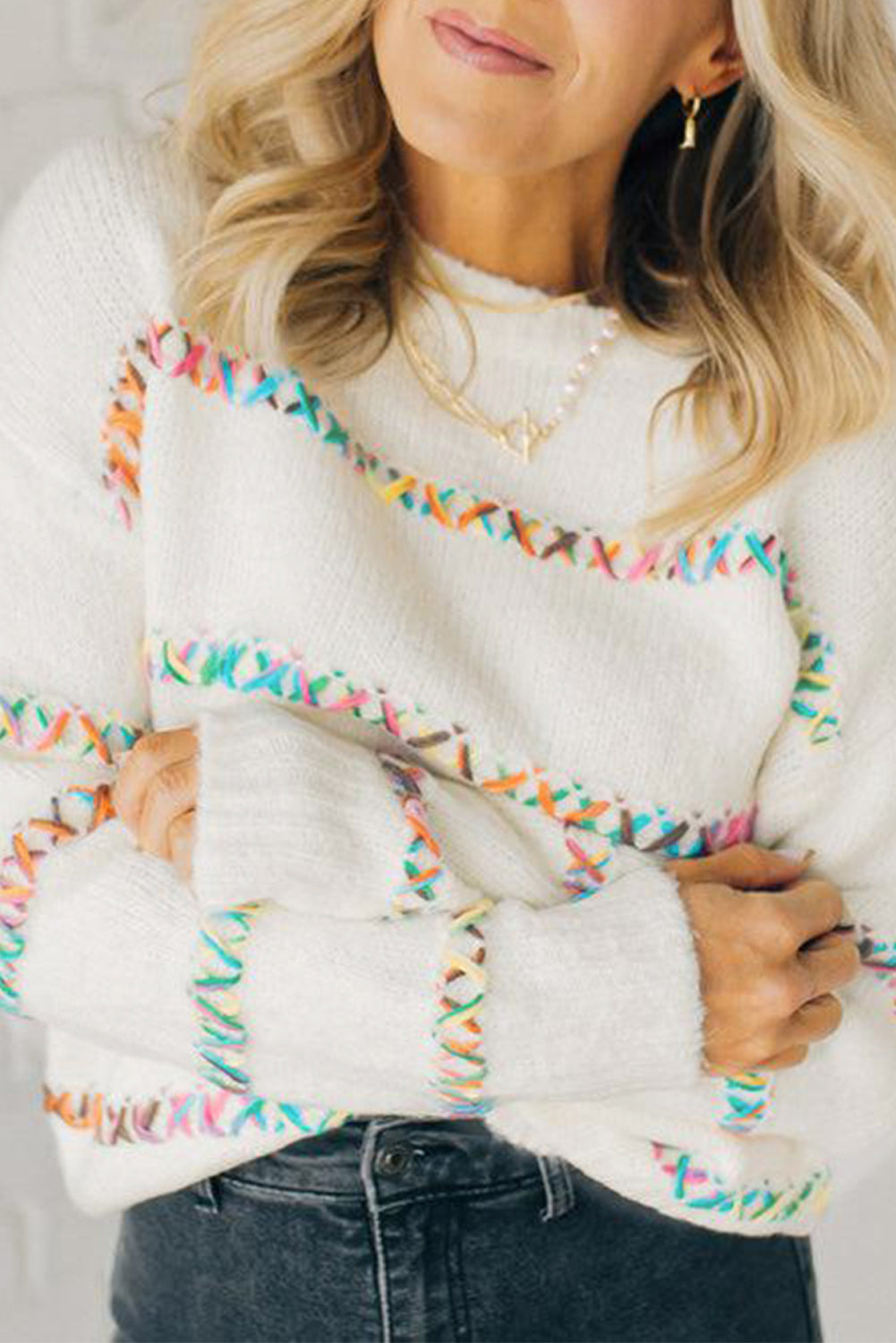 Weißer pullover mit gekreuzten schultern und bunten maschen
