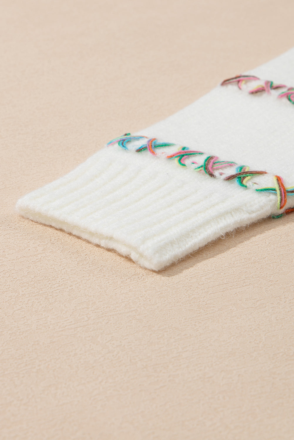 Weißer pullover mit gekreuzten schultern und bunten maschen