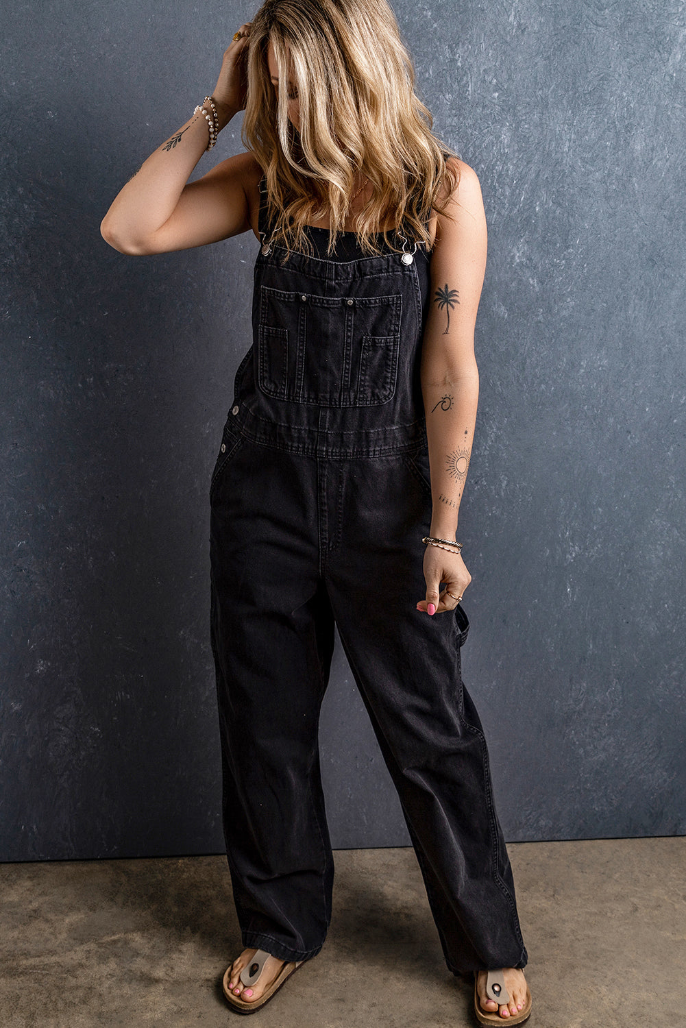 Schwarzer denim-overall mit verstellbaren schnallenriemen und mehreren taschen