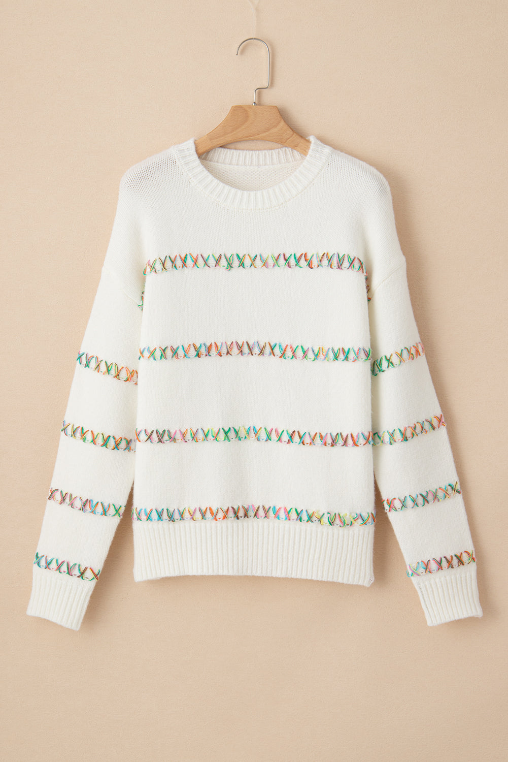 Weißer pullover mit gekreuzten schultern und bunten maschen