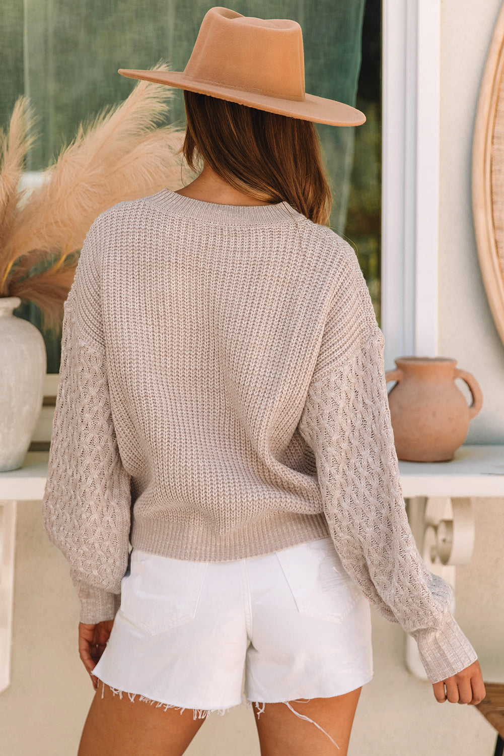 Pergamentfarbener pullover mit zopfstrickärmeln und hängeschultern