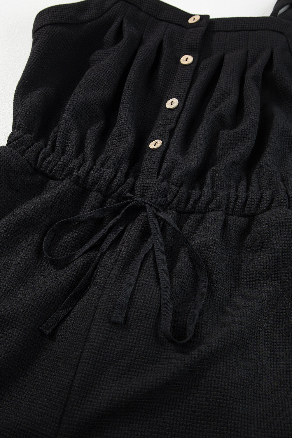 Schwarzer jumpsuit mit geknoteten trägern und strukturiertem kordelzug