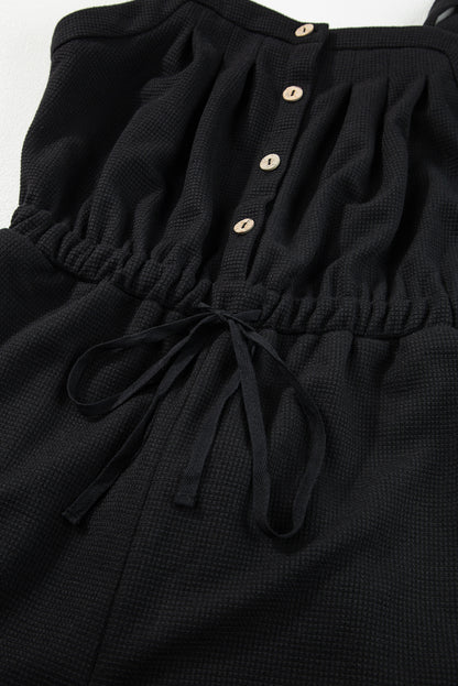 Schwarzer jumpsuit mit geknoteten trägern und strukturiertem kordelzug