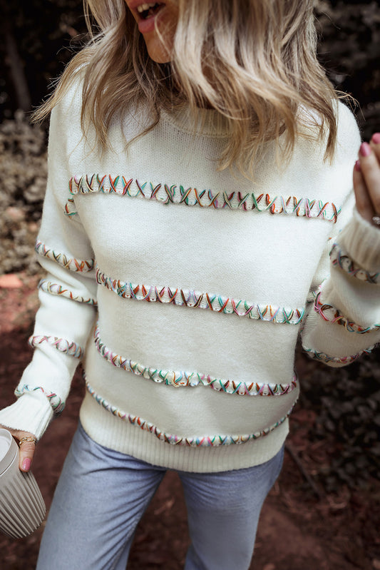 Weißer pullover mit gekreuzten schultern und bunten maschen