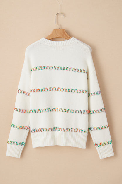 Weißer pullover mit gekreuzten schultern und bunten maschen