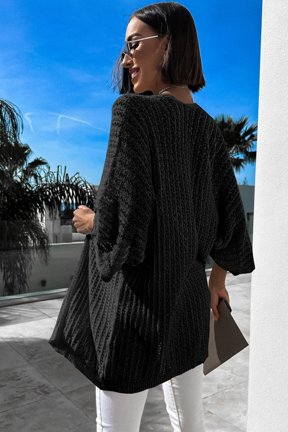 Schwarze strickjacke mit ausgehöhlten armbändern und ärmeln