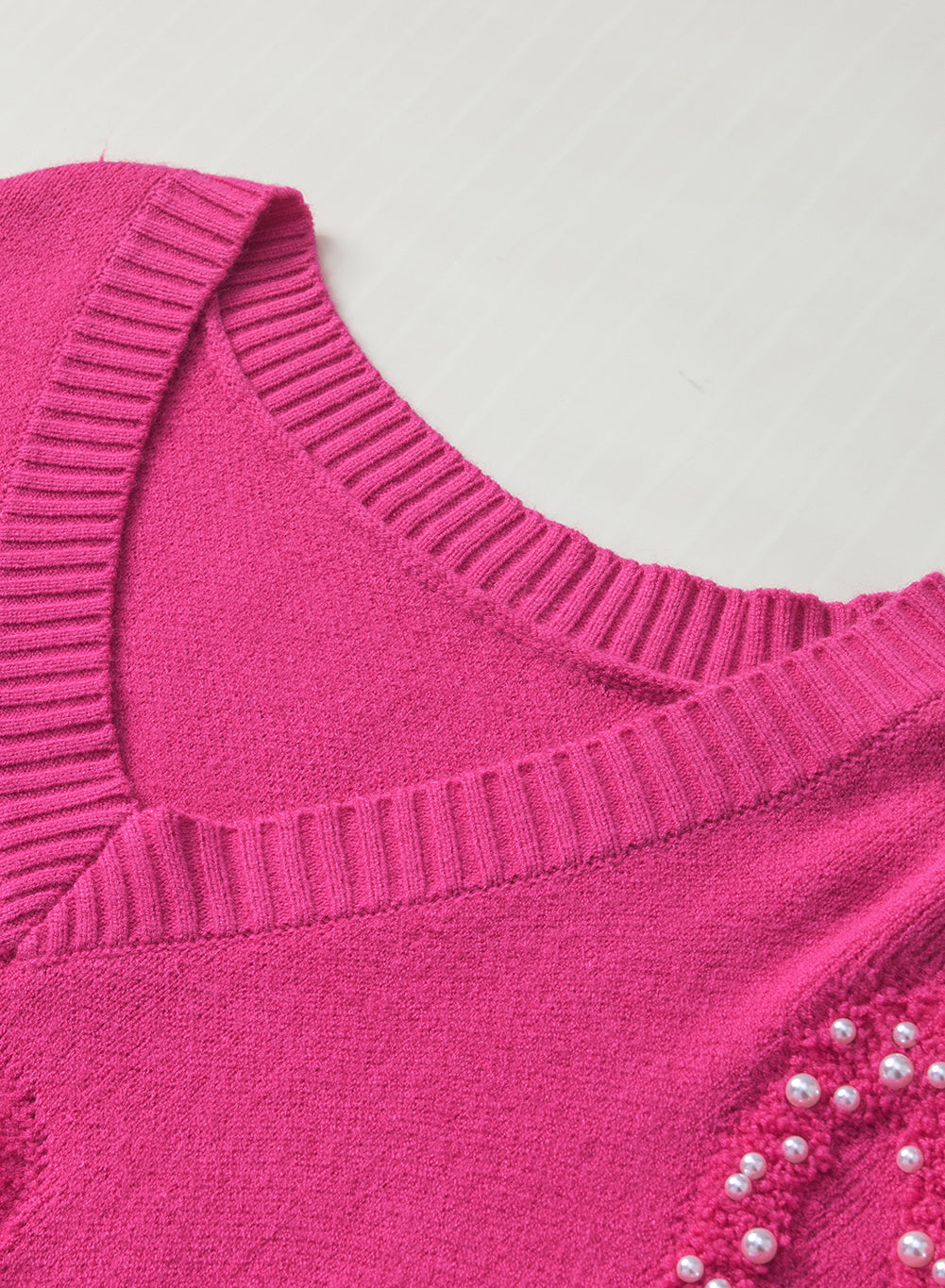 Rosenroter, perlenverzierter pullover mit v-ausschnitt und flauschigen herzen