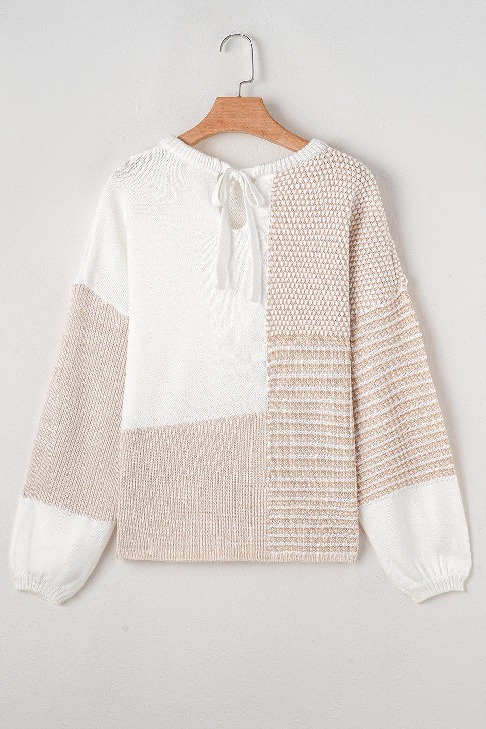 Haferflockenfarbener strickpullover mit gemischtem muster und schlüsselloch für die schultern