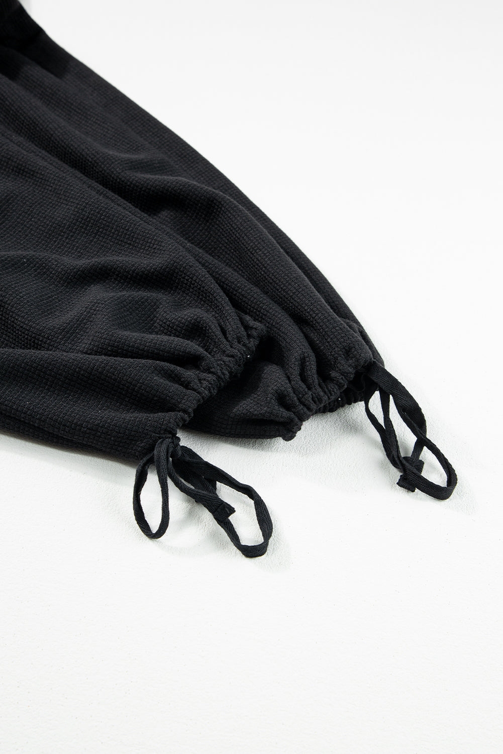 Schwarzer jumpsuit mit geknoteten trägern und strukturiertem kordelzug