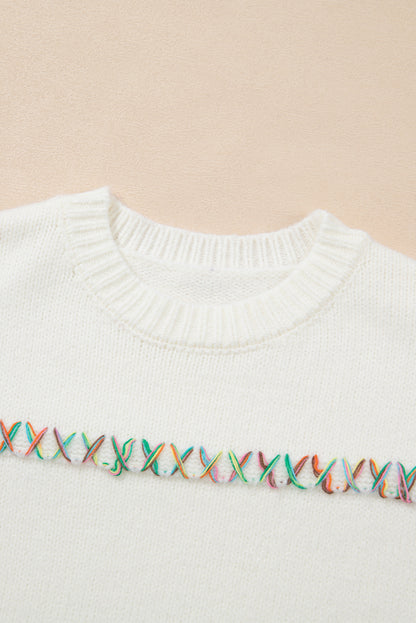 Weißer pullover mit gekreuzten schultern und bunten maschen
