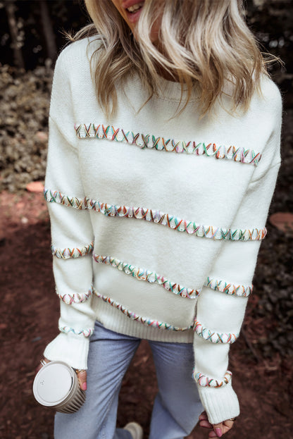 Weißer pullover mit gekreuzten schultern und bunten maschen