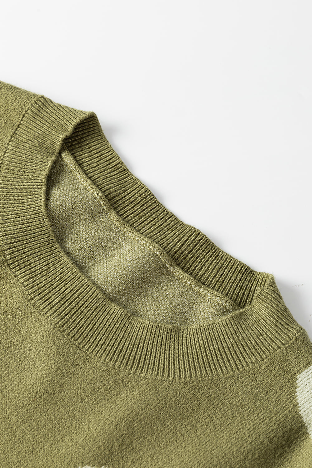 Spinatgrüner pullover mit großer blume und rippstrickmuster