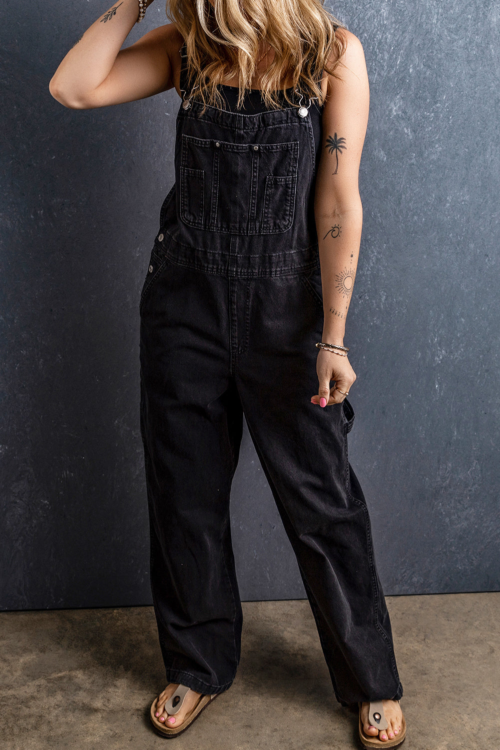 Schwarzer denim-overall mit verstellbaren schnallenriemen und mehreren taschen