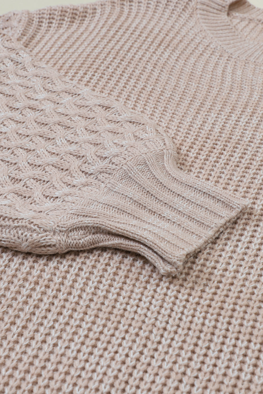 Pergamentfarbener pullover mit zopfstrickärmeln und hängeschultern