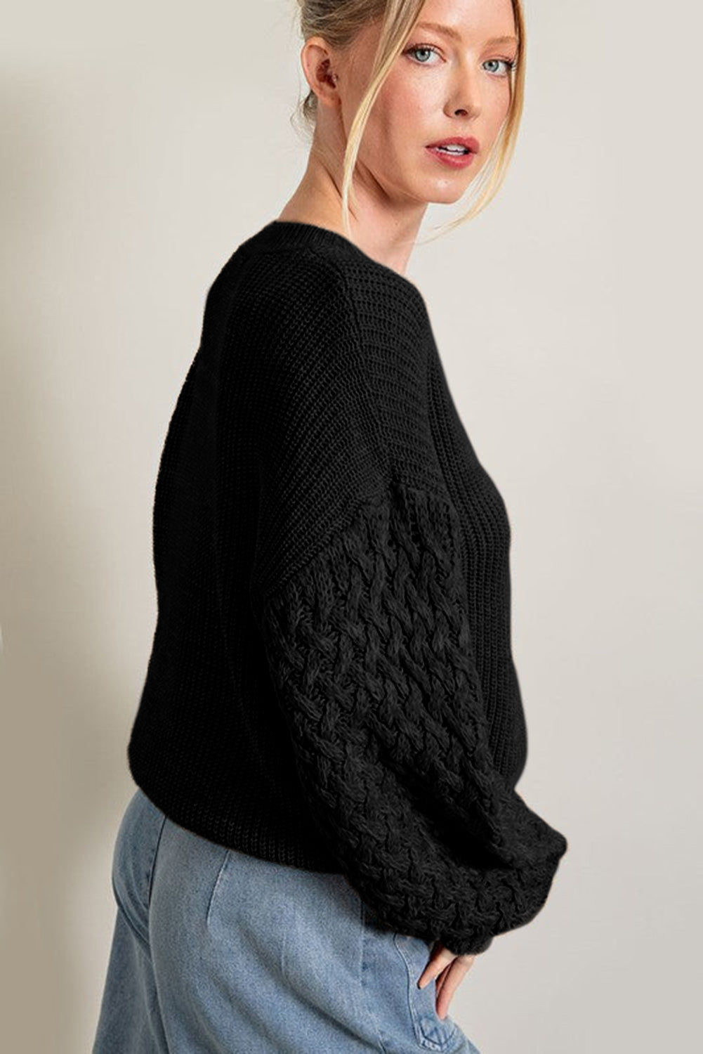 Schwarzer pullover mit zopfstrickärmeln und hängeschultern