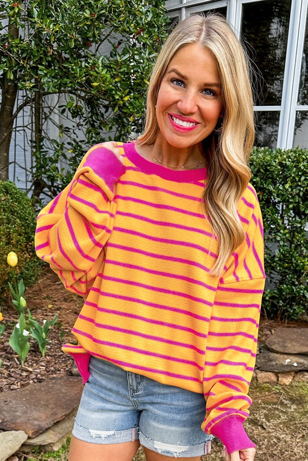 Orangefarbener gestreifter pullover mit rundhalsausschnitt und losen schultern