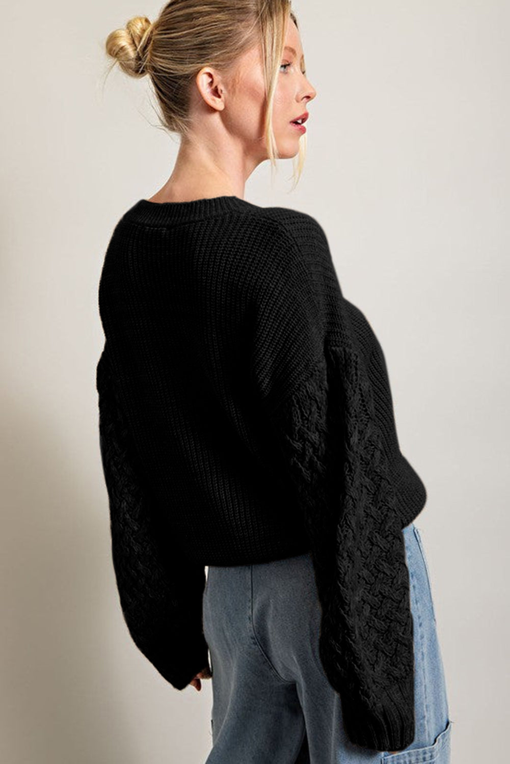 Schwarzer pullover mit zopfstrickärmeln und hängeschultern