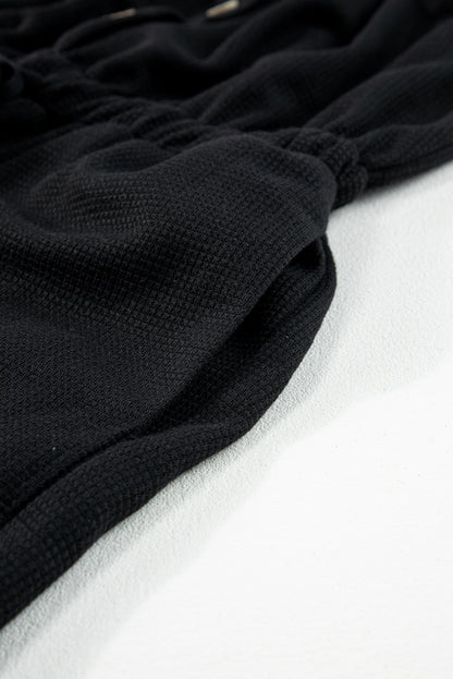 Schwarzer jumpsuit mit geknoteten trägern und strukturiertem kordelzug