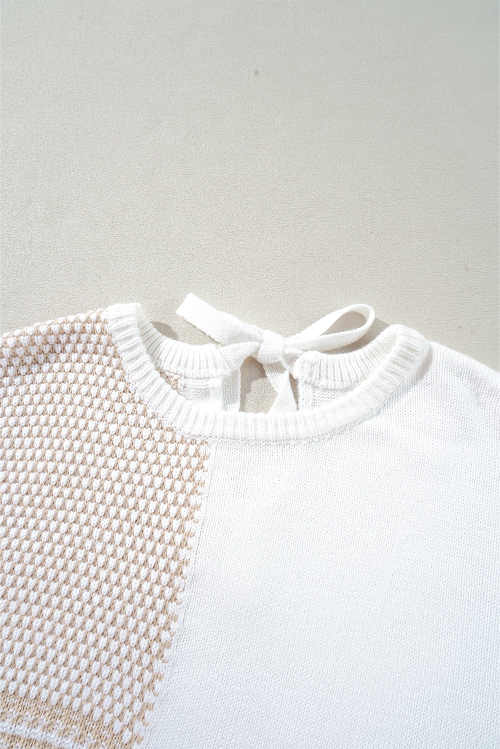 Haferflockenfarbener strickpullover mit gemischtem muster und schlüsselloch für die schultern