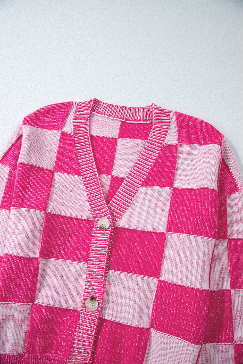 Rosa karierte strickjacke mit v-ausschnitt und geknöpften schultern
