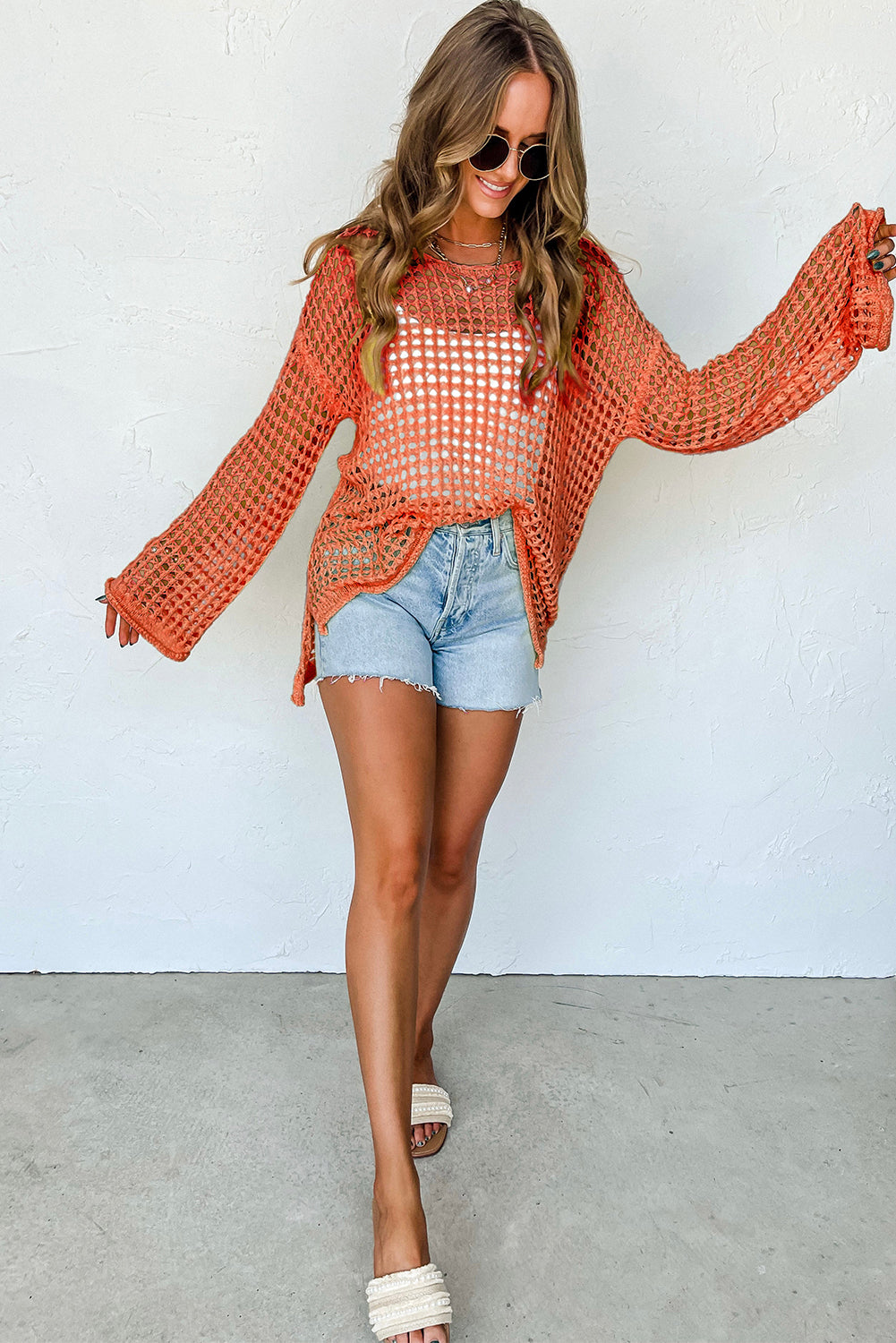 Orangefarbener tunika-pullover mit glockenärmeln und offenem häkelmuster