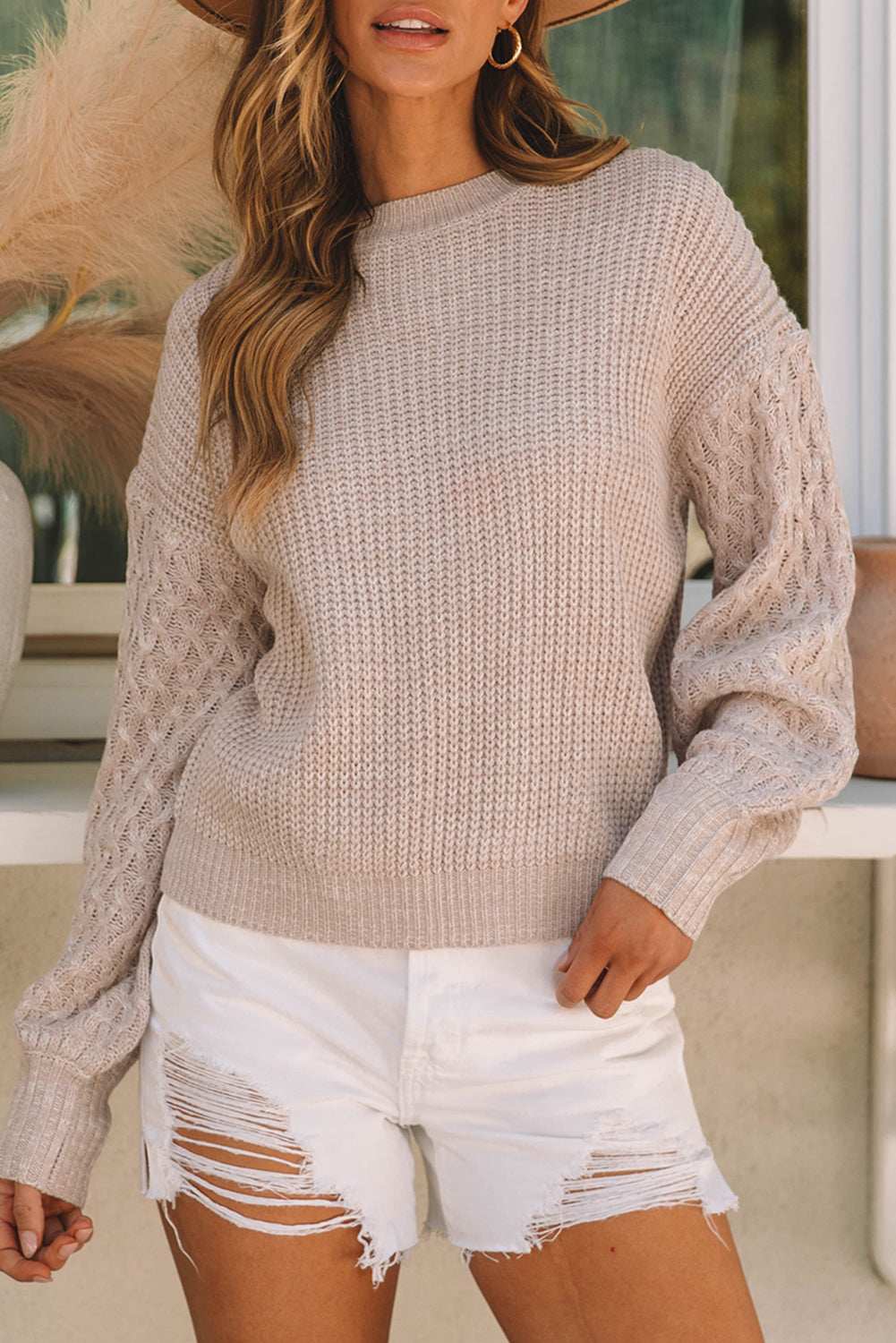 Pergamentfarbener pullover mit zopfstrickärmeln und hängeschultern