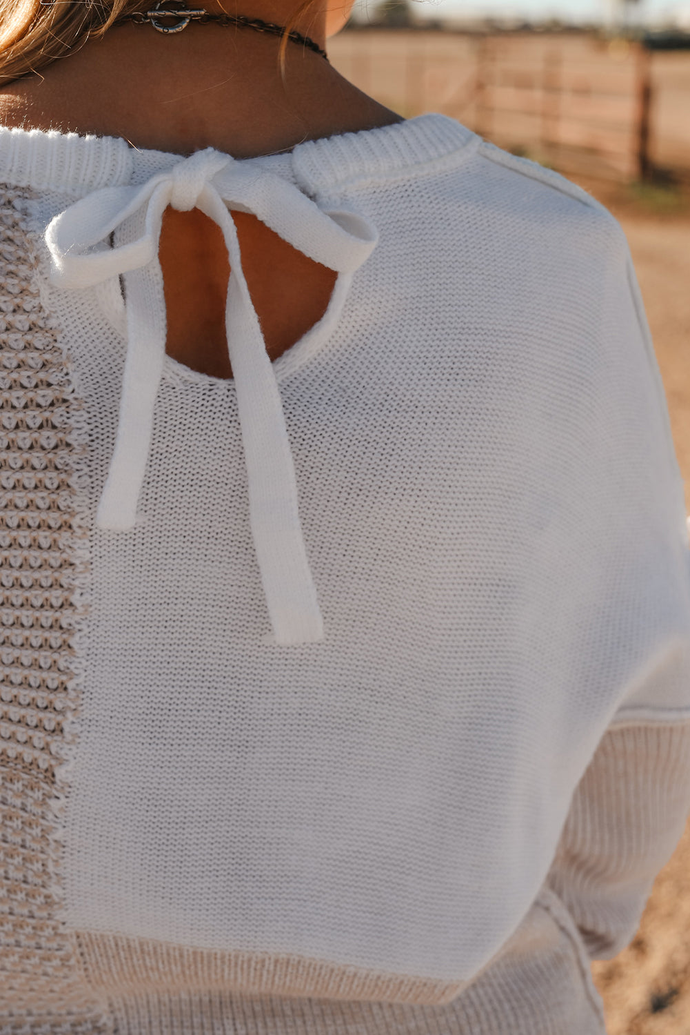 Haferflockenfarbener strickpullover mit gemischtem muster und schlüsselloch für die schultern