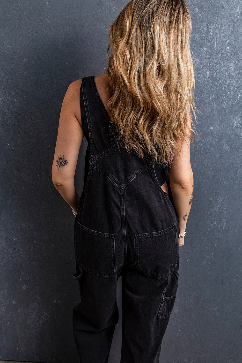 Schwarzer denim-overall mit verstellbaren schnallenriemen und mehreren taschen