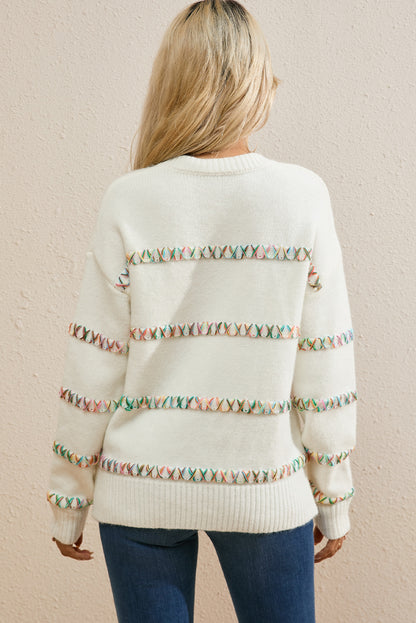 Weißer pullover mit gekreuzten schultern und bunten maschen