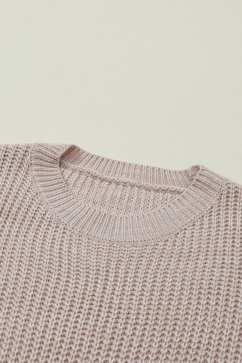 Pergamentfarbener pullover mit zopfstrickärmeln und hängeschultern