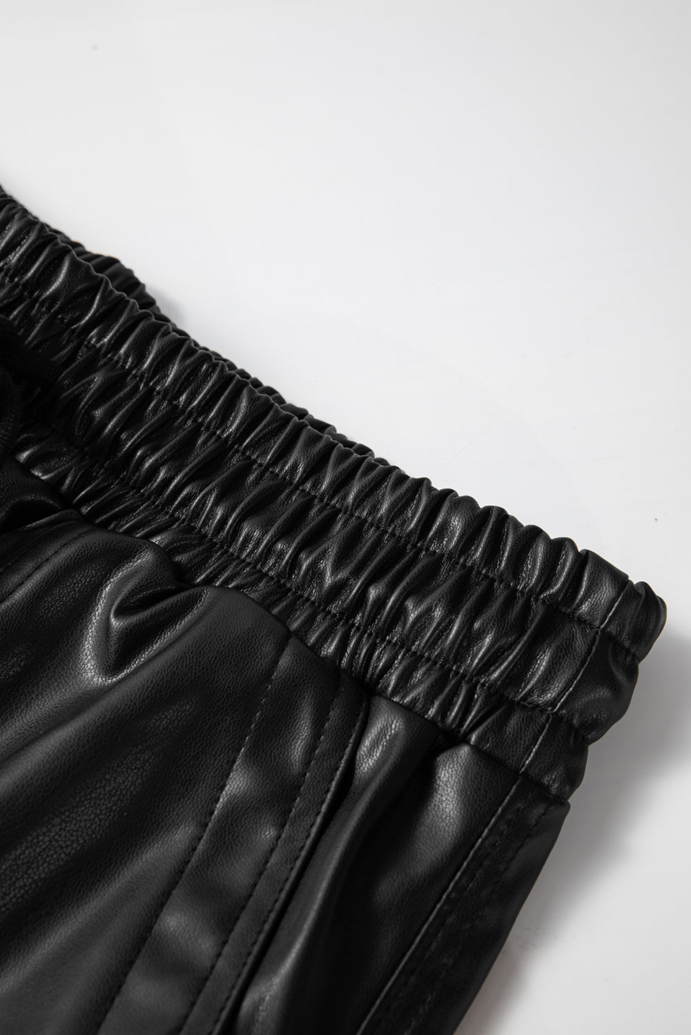 Schwarze kunstleder-jogginghose mit gesmokter taille und kordelzug