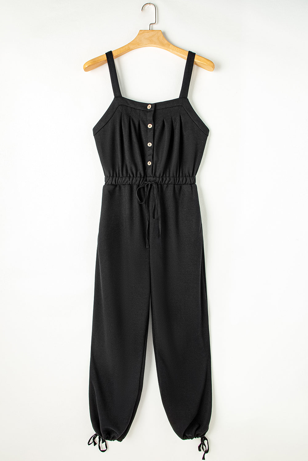 Schwarzer jumpsuit mit geknoteten trägern und strukturiertem kordelzug