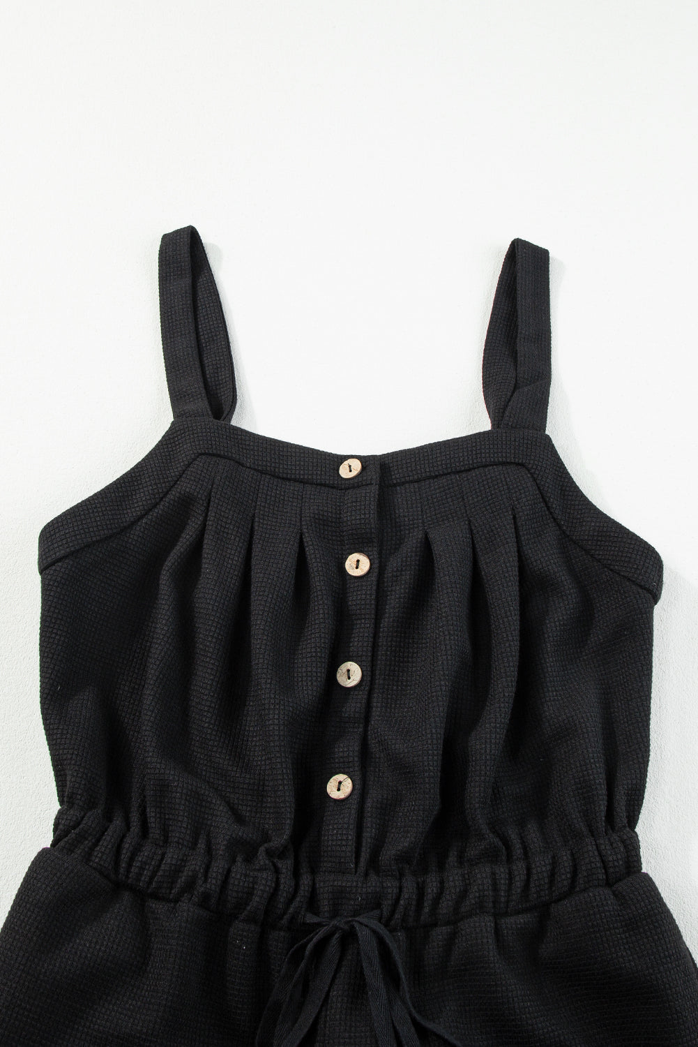 Schwarzer jumpsuit mit geknoteten trägern und strukturiertem kordelzug