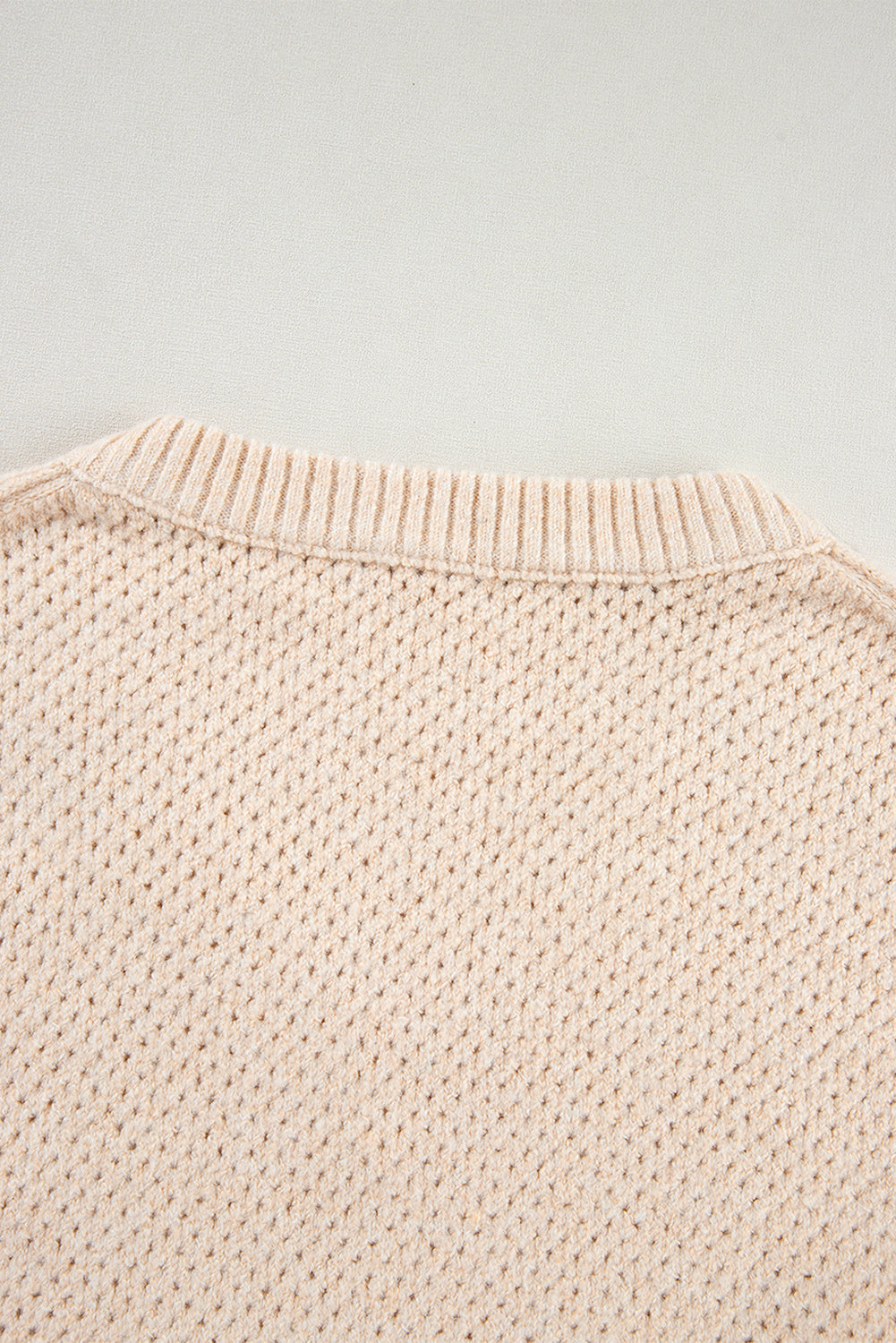 Pergamentfarbener pullover mit lockerem ösenausschnitt und tropfenschulter