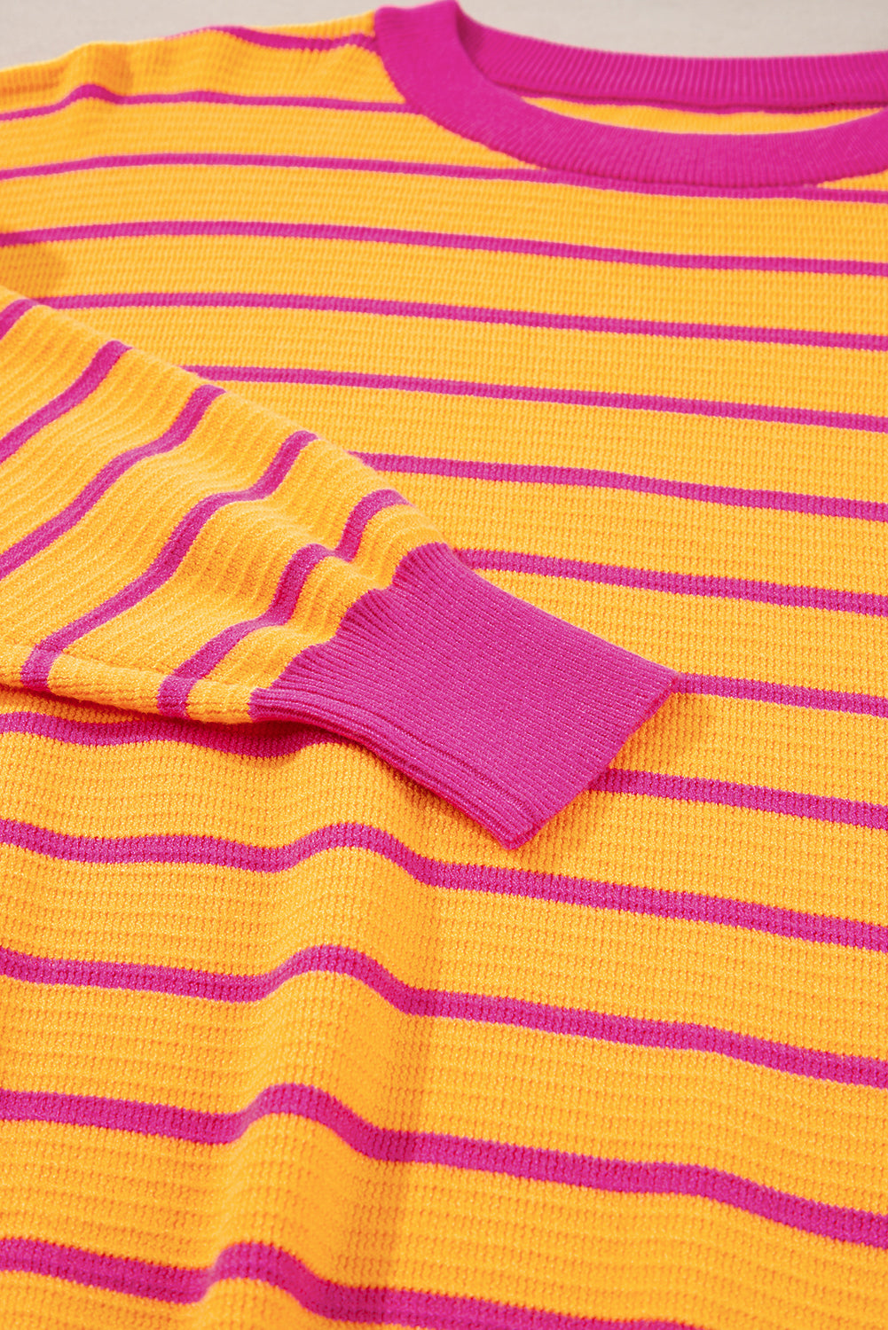 Orangefarbener gestreifter pullover mit rundhalsausschnitt und losen schultern