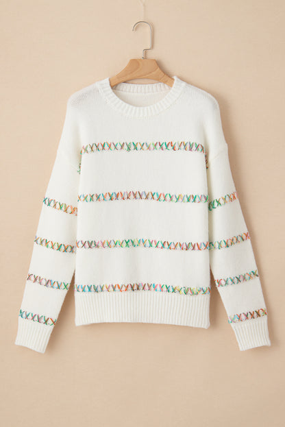 Weißer pullover mit gekreuzten schultern und bunten maschen
