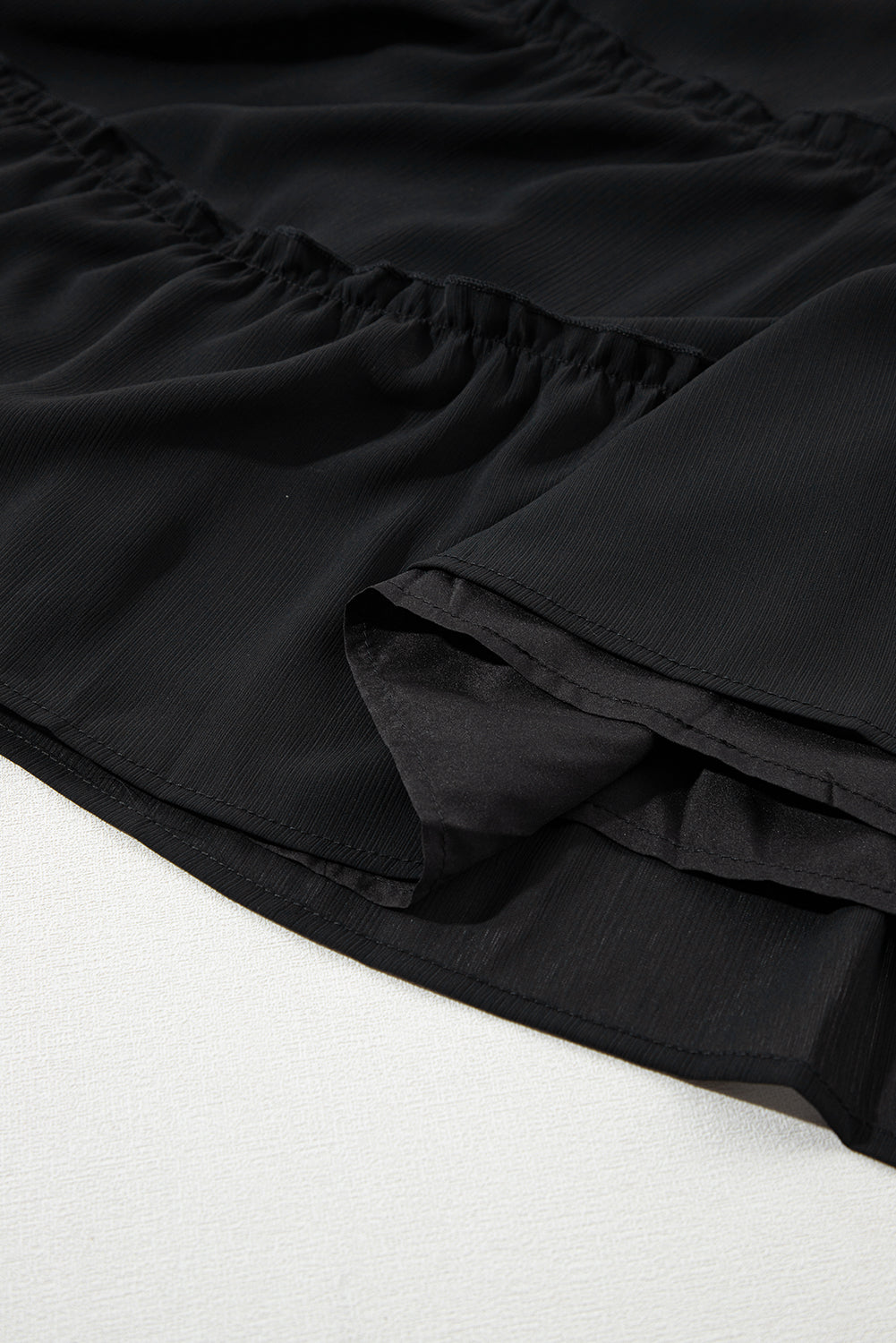 Schwarzes ärmelloses kleid mit v-ausschnitt und rüschenbesatz